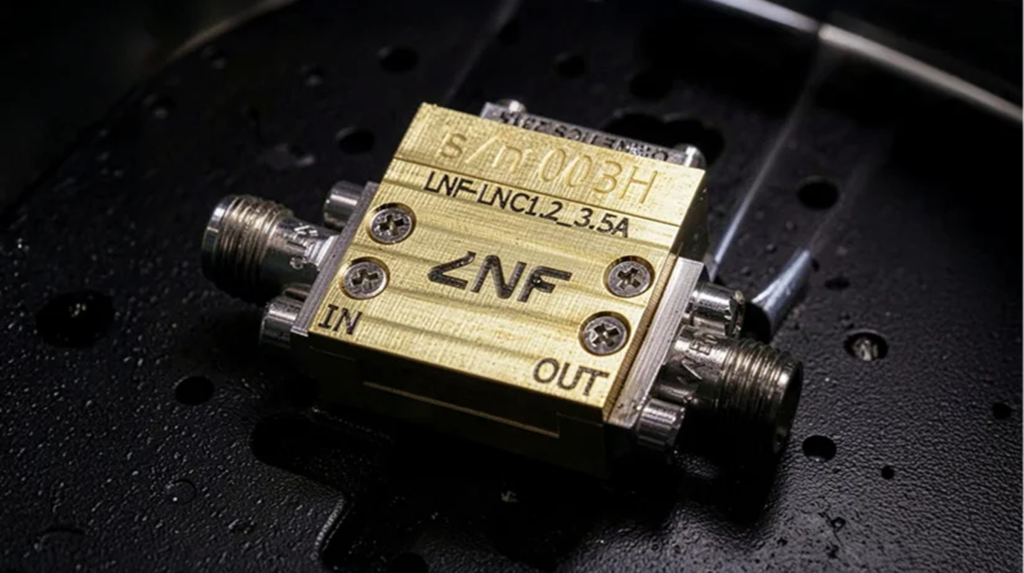 Close-up of a cryogenic low noise amplifier with RF connectors labeled IN and OUT.